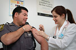 Free Stock Photo: A police officer receiving a vaccination shot from his doctor