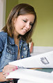 Free Stock Photo: The woman pictured here turning the page of her reference book, was researching what appeared to be a graphic design-based project, and was using both conventional hard copy text books, as well as her laptop computer in order to investigate offerings found on the Internet.