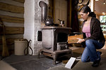Free Stock Photo: A woman placing wood into a stove