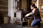 Free Stock Photo: A woman placing wood into a stove