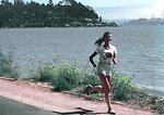 Free Stock Photo: Shown is a Caucasian woman in shorts and t-shirt running along a lake shore.