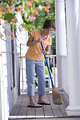 Free Stock Photo: A woman sweeping her front porch