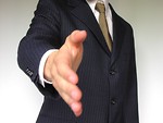Free Stock Photo: Business man in a blue suit extending his hand for a handshake.