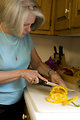 Free Stock Photo: The woman depicted in this image was shown in her kitchen, as she was in the process of preparing a healthy salad, which can be seen in the background, contained in a large glass bowl. At this point in the salad preparation, she was cutting a yellow bell pepper atop a clean white cutting board, the slices of which would then be added to the salad mixture. Note the clean, orderly, uncluttered countertop, which is important to the maintenance of a proper kitchen environment. It is very important to prepare foods in as clean environment as possible, thereby, minimizing the possibility of introducing foodborne contaminants into the food preparation process.
