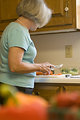 Free Stock Photo: This image depicts a woman in her kitchen, as she was in the process of preparing fresh vegetables for her meal. At this point of the process, she was slicing a thoroughly-washed carrot atop a clean cutting board. Note that her sink\'s counter top area was sanitary, and clutter-free. The glass bowl in the background already contained prepared broccoli and lettuce. It is very important to prepare foods in as clean environment as possible, thereby, minimizing the possibility of introducing foodborne contaminants into the food preparation process.