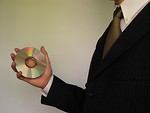 Free Stock Photo: A business man in suit and tie holding a compact disc.