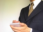 Free Stock Photo: Business man in a blue suit writing on a memo pad.