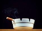 Free Stock Photo: A cigarette burning in a white ashtray