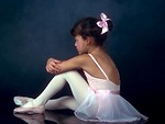 Free Stock Photo: A young ballerina posing on the floor with a dark background