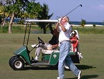 Free Stock Photo: Man swinging a golf club standing next to a golf cart