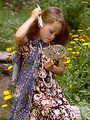 Free Stock Photo: A young girl combing her hair with a mirror outside