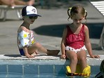 Free Stock Photo: A young girl and boy sitting by a pool