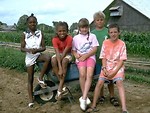 Free Stock Photo: A group of kids sitting on a wheelbarrow on a farm