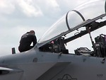 Free Stock Photo: A maintenance crew member sitting on an F-18 fighter jet
