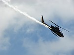 Free Stock Photo: An AH-1F Cobra attack helicopter flying in the sky with a smoke trail