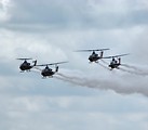 Free Stock Photo: Four AH-1F Cobra attack helicopters flying with smoke trails in the sky