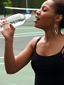 Free Stock Photo: A beautiful teen African American girl drinking water on a tennis court