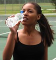 Free Stock Photo: A beautiful teen African American girl drinking water on a tennis court