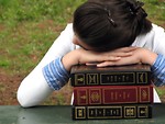 Free Stock Photo: A young schoolgirl resting her head on a stack of books