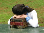Free Stock Photo: A young schoolgirl resting her head on a stack of books