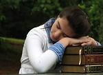 Free Stock Photo: A young schoolgirl resting her head on a stack of books