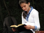 Free Stock Photo: A young schoolgirl reading a book outside