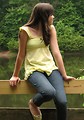 Free Stock Photo: A beautiful young girl sitting on a wooden fence by a lake.