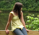 Free Stock Photo: A beautiful young girl sitting on a wooden fence by a lake