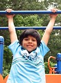 Free Stock Photo: A young latino boy hanging from bars on a playground