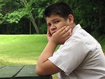 Free Stock Photo: A teen latino boy sitting at an outdoor table looking worried