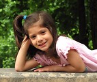Free Stock Photo: A cute young latina girl posing outdoors on a stone wall