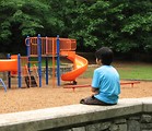 Free Stock Photo: A young latino boy sitting on a wall by a playground
