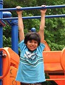 Free Stock Photo: A young latino boy hanging from bars on a playground