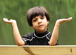 Free Stock Photo: A young latino boy with a confused expression posing by a lake