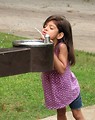 Free Stock Photo: A cute young latina girl drinking from a water fountain