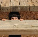 Free Stock Photo: A young latino boy playing behind wooden steps