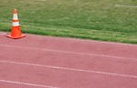 Free Stock Photo: A running track by a field with an orange cone