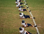 Free Stock Photo: High school football players doin warm up exercises on a field